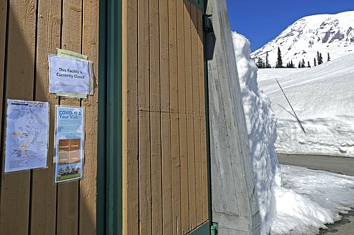 Signs offer tips for preventing the spread of the new coronavirus, as well as the closed status of the Henry M. Jackson Visitor Center, at Paradise, Wednesday, March 18, 2020, at Mount Rainier National Park in Washington state. Most national parks are remaining open during the outbreak of the new coronavirus, but many are closing visitor centers, shuttles, lodges and restaurants in hopes of containing the spread of the coronavirus. (AP Photo/Ted S. Warren)