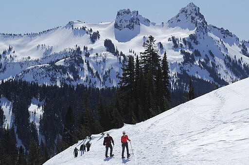 Snowshoers head up a slope above Paradise at Mount Rainier National Park, Wednesday, March 18, 2020, in Washington state. Most national parks are remaining open during the outbreak of the new coronavirus, but many are closing visitor centers, shuttles, lodges and restaurants in hopes of containing its spread. (AP Photo/Ted S. Warren)