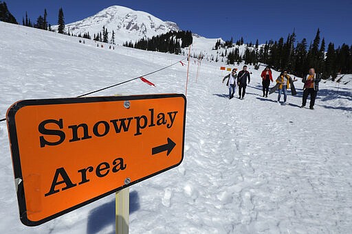 Visitors to Mount Rainier National Park walk away from the sledding area at Paradise, Wednesday, March 18, 2020, in Washington state. Most national parks are remaining open during the outbreak of the new coronavirus, but many are closing visitor centers, shuttles, lodges and restaurants in hopes of containing its spread. (AP Photo/Ted S. Warren)