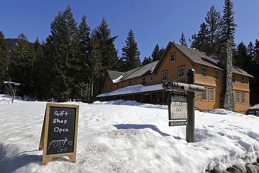 A sign at the National Park Inn at Longmire offers food orders to-go from the inn's restaurant at Mount Rainier National Park, Wednesday, March 18, 2020, in Washington state. Most national parks are remaining open during the outbreak of the new coronavirus, but many are closing visitor centers, shuttles, lodges and restaurants in hopes of containing its spread. (AP Photo/Ted S. Warren)