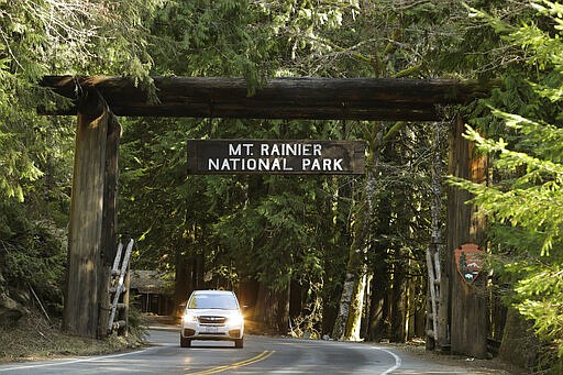 A car passes through the entrance to Mount Rainier National Park, Wednesday, March 18, 2020, in Washington state. Most national parks are remaining open during the outbreak of the new coronavirus, but many are closing visitor centers, shuttles, lodges and restaurants in hopes of containing its spread. (AP Photo/Ted S. Warren)