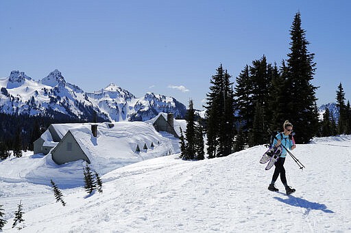 A snowshoer walks near the Paradise Inn at Mount Rainier, which is closed for the winter, at Mount Rainier National Park, Wednesday, March 18, 2020, in Washington state. Most national parks are remaining open during the outbreak of the new coronavirus, but many are closing visitor centers, shuttles, lodges and restaurants in hopes of containing its spread. (AP Photo/Ted S. Warren)