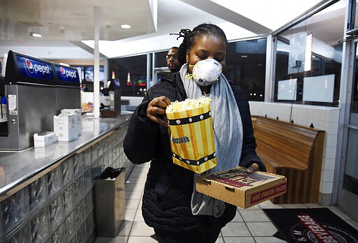 Andrea Wyatt of Inglewood, Calif., wears a mask as she collects her concessions at the Paramount Drive-In Theatres, Thursday, March 19, 2020, in Paramount, Calif. The drive-in theater, long a dwindling nostalgia act in a multiplex world, is experiencing a momentary return to prominence. With nearly all of the nation&#146;s movie theaters shuttered due to the pandemic, some drive-in owners think they&#146;re in a unique position to give moviegoers a chance to do something out of the house but stay within prudent distance from one another. (AP Photo/Chris Pizzello)