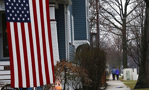 In this March 19, 2020, photo, a family takes a walk in Oak Park, Ill., before a two-week &quot;shelter in place&quot; order goes into effect. Leaders in the Chicago suburb were the first in the state to take the step, requiring non-essential businesses to close, to try to curb the spread of the coronavirus. (AP Photo/Martha Irvine)