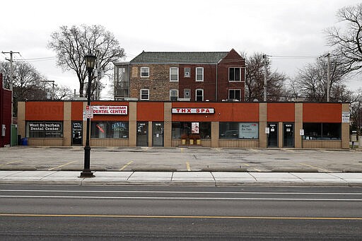 A parking lot in the Village of Oak Park, Ill., sits empty where small businesses are closed, Friday, March 20, 2020. There are at least three confirmed cases of COVID-19 in Oak Park, just nine miles from downtown Chicago, where the mayor has ordered residents to shelter in place. With so few tests available, surely there are others, says Tom Powers, spokesman for the village of about 52,000 in a metropolitan area with millions. (AP Photo/Charles Rex Arbogast)