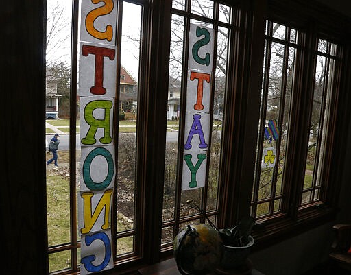 A man walks past a window in Oak Park, Ill., on Friday, March 20, 2020, before a two-week &quot;shelter in place&quot; order goes into effect. Leaders in the Chicago suburb were the first in the state to take the step, requiring non-essential businesses to close, to try to curb the spread of the coronavirus. (AP Photo/Martha Irvine)