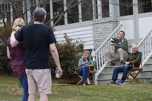 Residents of Brookfield Road in Montclair, N.J., get together for a street happy hour toast Friday, March 20, 2020. With bars shuttered and stressed-out workers stuck at home, companies and friend groups across the U.S. are holding happy hours over video chat to commiserate and keep spirits high amid the new coronavirus pandemic. In one community, neighbors are toasting to one another every night from the ends of their driveways to unwind &#151; while keeping a safe distance, of course. (AP Photo/Mary Altaffer)