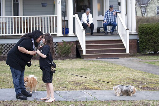 Residents of Brookfield Road in Montclair, N.J., get together for a street happy hour toast Friday, March 20, 2020. With bars shuttered and stressed-out workers stuck at home, companies and friend groups across the U.S. are holding happy hours over video chat to commiserate and keep spirits high amid the new coronavirus pandemic. In one community, neighbors are toasting to one another every night from the ends of their driveways to unwind. (AP Photo/Mary Altaffer)