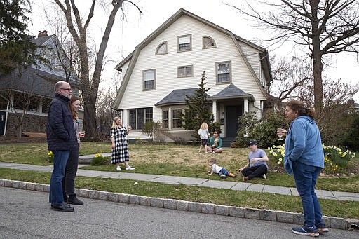 Residents of Brookfield Road in Montclair, N.J., get together for a street happy hour toast Friday, March 20, 2020. With bars shuttered and stressed-out workers stuck at home, companies and friend groups across the U.S. are holding happy hours over video chat to commiserate and keep spirits high amid the new coronavirus pandemic. In one community, neighbors are toasting to one another every night from the ends of their driveways to unwind &#151; while keeping a safe distance, of course. (AP Photo/Mary Altaffer)