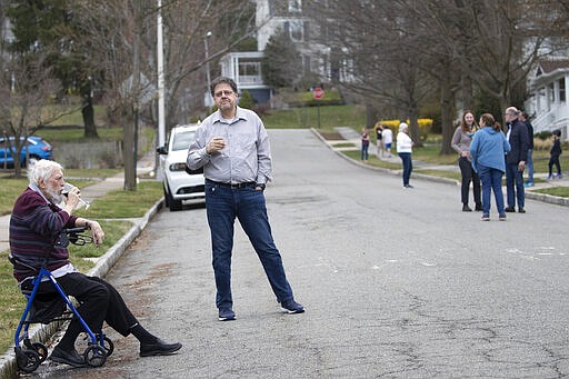 Residents of Brookfield Road in Montclair, N.J., get together for a street happy hour toast Friday, March 20, 2020. With bars shuttered and stressed-out workers stuck at home, companies and friend groups across the U.S. are holding happy hours over video chat to commiserate and keep spirits high amid the new coronavirus pandemic. In one community, neighbors are toasting to one another every night from the ends of their driveways to unwind &#151; while keeping a safe distance, of course. (AP Photo/Mary Altaffer)