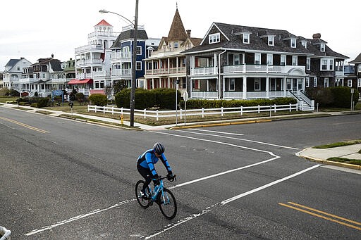 A cyclist rides a bicyle in Cape May, N.J., Wednesday, March 18, 2020.Some people who live in cities or their suburbs have been fleeing to their second homes at the shore to ride out the coronavirus near the beach. But neighbors in many of those towns are yanking the welcome mat, fearing infection and an overwhelming of already-stretched resources.  (AP Photo/Matt Rourke)