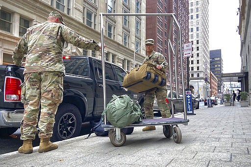 Members of the National Guard unload bags and head inside the SpringHill Suites Marriott in downtown Baltimore, M.D. (Ulysses Mu&ntilde;oz/The Baltimore Sun via AP)