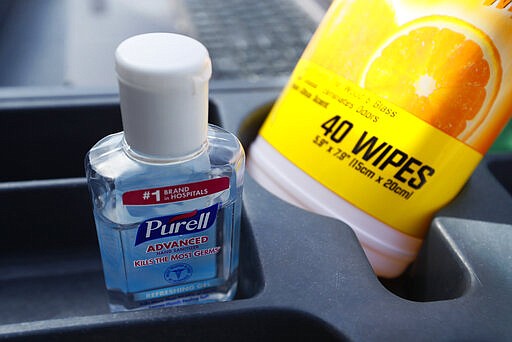 In this Tuesday, March 17, 2020, photo hand sanitizer and cleaner wipes sit in a cart as Des Moines Area Religious Council food pantry worker Patrick Minor passes out food at a senior center in Des Moines, Iowa. The Associated Press has found that the critical shortage of testing swabs, protective masks, surgical gowns and hand sanitizer can be tied to a sudden drop in imports of medical supplies. (AP Photo/Charlie Neibergall)