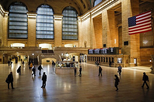 A MTA conductor stands in a light beam at Grand Center Terminal that is sparsely populated during rush hour due to COVID-19 concerns, Friday, March 20, 2020, in New York. New York Gov. Andrew Cuomo is ordering all workers in non-essential businesses to stay home and banning gatherings statewide. &quot;Only essential businesses can have workers commuting to the job or on the job,&quot; Cuomo said of an executive order he will sign Friday. Nonessential gatherings of individuals of any size or for any reason are canceled or postponed. (AP Photo/John Minchillo)