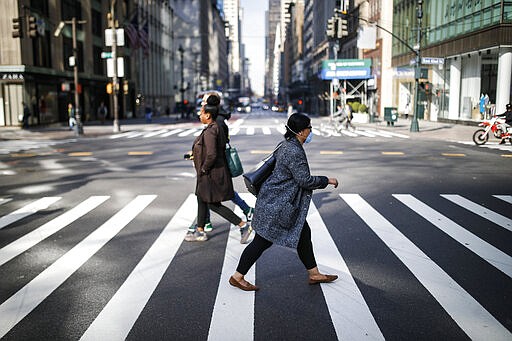 A pedestrian wearing a protective mask hurries across 5th Avenue that is sparsely populated due to COVID-19 concerns, Friday, March 20, 2020, in New York. New York Gov. Andrew Cuomo is ordering all workers in non-essential businesses to stay home and banning gatherings statewide. &quot;Only essential businesses can have workers commuting to the job or on the job,&quot; Cuomo said of an executive order he will sign Friday. Nonessential gatherings of individuals of any size or for any reason are canceled or postponed. (AP Photo/John Minchillo)