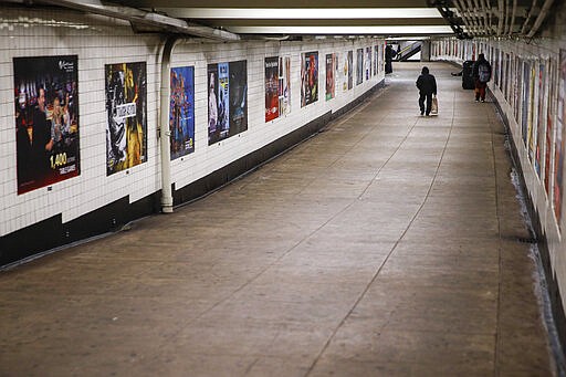 A subway customer walks through an empty underground passage in the Brooklyn borough of New York, Monday, March 16, 2020. New York leaders took a series of unprecedented steps Sunday to slow the spread of the coronavirus, including canceling schools and extinguishing most nightlife in New York City.  According to the World  Health Organization, most people recover in about two to six weeks, depending on the severity of the illness.  (AP Photo/John Minchillo)