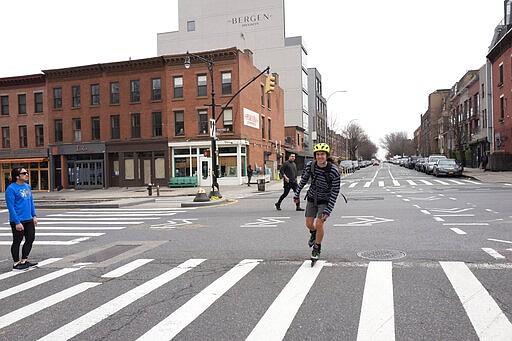 A man rollerblades along a quiet Brooklyn street, Friday, March 20, 2020 in New York. (AP Photo/Mark Lennihan)