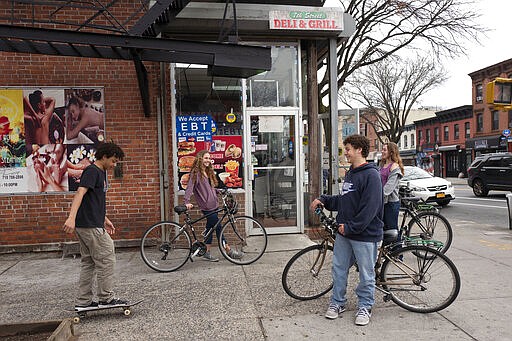 High school students hang out on a Brooklyn street corner, Friday, March 20, 2020 in New York. The city's public schools are closed due to the coronavirus. (AP Photo/Mark Lennihan)