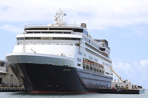 UPDATES THAT A FEW PASSENGERS WERE ALLOWED OFF THE SHIP FRIDAY - The Maasdam, operated by Holland America Line, is docked in Honolulu Harbor, for a re-supply Friday, March 20, 2020, in Honolulu. Six Hawaii residents were allowed to leave the cruise ship and two other U.S. citizens were allowed to disembark for medical reasons. (AP Photo/Marco Garcia)