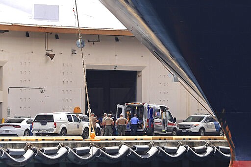 State officials and a medical crew are seen near the Maasdam cruise ship while it is docked in Honolulu Harbor for a re-supply Friday, March 20, 2020, in Honolulu. Six Hawaii residents were allowed to leave the cruise ship and two other U.S. citizens were allowed to disembark for medical reasons. While there are no positive cases of coronavirus on the ship, state transportation officials declined to allow any other passengers off the ship. (AP Photo/Marco Garcia)