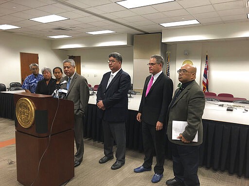 House Speaker Scott Saiki, at podium in center, speaks to reporters while flanked by representatives and senators at the Hawaii State Capitol on Monday, March 16, 2020. Hawaii lawmakers are indefinitely suspending the current state legislative session to prevent the spread of the new coronavirus. (AP Photo/Audrey McAvoy)