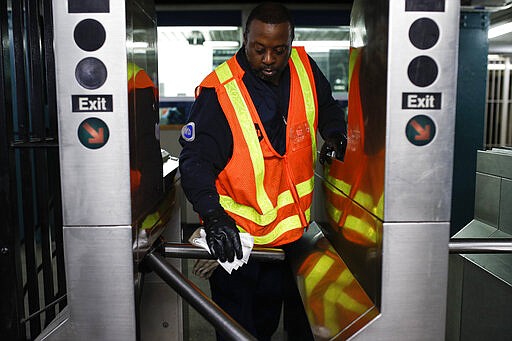 An MTA employee sanitizes surfaces at the CLasson Ave. and Lafayette Ave. subway station with bleach solutions due to COVID-19 concerns, Friday, March 20, 2020, in the Brooklyn Borough in New York. New York Gov. Andrew Cuomo is ordering all workers in non-essential businesses to stay home and banning gatherings statewide. &quot;Only essential businesses can have workers commuting to the job or on the job,&quot; Cuomo said of an executive order he will sign Friday. Nonessential gatherings of individuals of any size or for any reason are canceled or postponed. (AP Photo/John Minchillo)