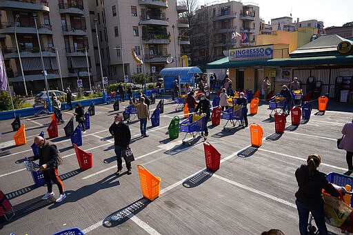 People stand apart as they line up to enter a supermarket in Rome, Friday, March 20, 2020. For most people, the new coronavirus causes only mild or moderate symptoms. For some it can cause more severe illness.  (AP Photo/Andrew Medichini)