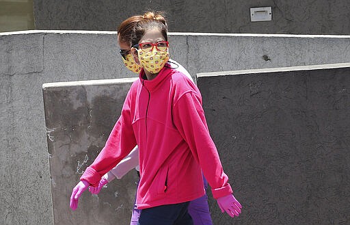 Women wear face masks and gloves as a precaution against the spread of the new coronavirus, in Quito, Ecuador, Thursday, March 19, 2020. The government has declared a &quot;health emergency,&quot; restricting movement to only those who provide basic services, enacting a curfew, and closing schools. (AP Photo/Dolores Ochoa)