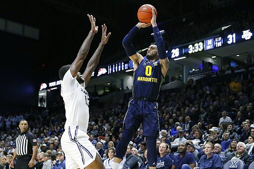 FILE - In this Jan. 29, 2020, file photo, Marquette's Markus Howard (0) shoots over Xavier's Naji Marshall (13) during the first half of an NCAA college basketball game in Cincinnati. Howard was selected to The Associated Press All-America first team, Friday, March 20, 2020. (AP Photo/John Minchillo, Fle)