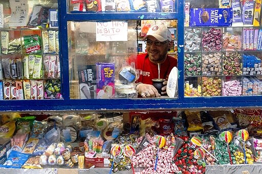 In this March 18, 2020 photo, Ivan holds his &quot;mate&quot; inside a candy kiosk as he works in Montevideo, Uruguay. Not withstanding the new coronavirus emergency he still shares his mate with folks that work nearby, however there are much less people to share and most of the time he drinks alone. For most people, COVID-19 causes only mild or moderate symptoms. For some it can cause more severe illness. (AP Photo/Matilde Campodonico)