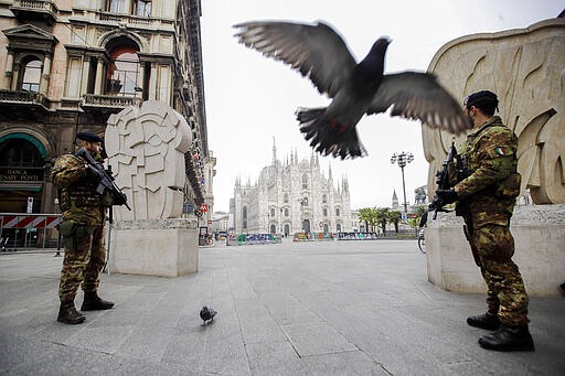 Italian soldiers patrol as the Duomo gothic cathedral is visible in background, in Milan, Friday, March 20, 2020. Mayors of many towns in Italy are asking for ever more stringent measures on citizens' movements to help contain the surging infections of the coronavirus. For most people, the new coronavirus causes only mild or moderate symptoms. For some it can cause more severe illness. (AP Photo/Luca Bruno)