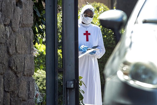 A nun wearing a mask and gloves stands at the Istituto Figlie di San Camillo (Institute of Daughters of St. Camillo) in Grottaferrata, near Rome, Friday, March 20, 2020. Outbreaks of the coronavirus have stricken two convents in the Rome area. Rome daily Il Messaggero quoted the Lazio region's health commissioner on Friday as saying 59 nuns at the Institute of Daughters of St. Camillo in the hill town of Grottaferrata have tested positive for COVID-19. For most people, the new coronavirus causes only mild or moderate symptoms. For some it can cause more severe illness. (Roberto Monaldo/LaPresse via AP)