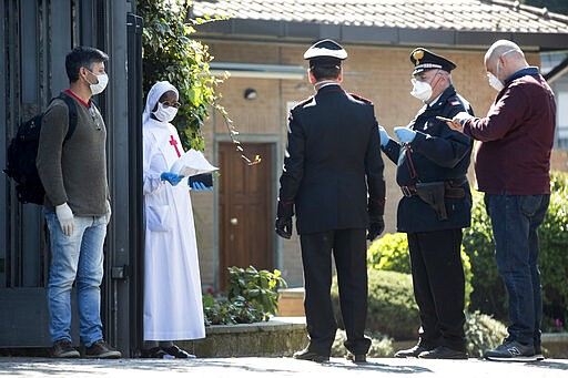 A nun talks with Carabinieri officers at the entrance of the Istituto Figlie di San Camillo (Institute of Daughters of St. Camillo) in Grottaferrata, near Rome, Friday, March 20, 2020. Outbreaks of the coronavirus have stricken two convents in the Rome area. Rome daily Il Messaggero quoted the Lazio region's health commissioner on Friday as saying 59 nuns at the Institute of Daughters of St. Camillo in the hill town of Grottaferrata have tested positive for COVID-19. For most people, the new coronavirus causes only mild or moderate symptoms. For some it can cause more severe illness. (Roberto Monaldo/LaPresse via AP)