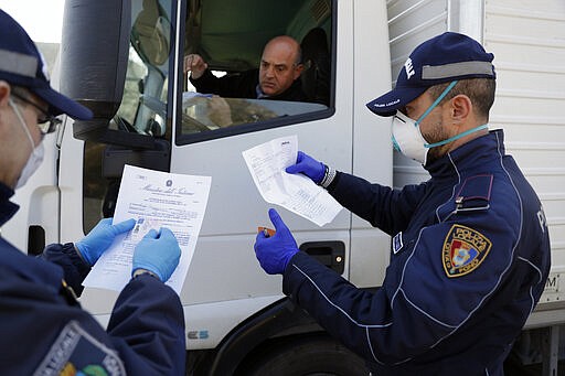 City police officers check a truck driver in Fondi, near Rome, Friday, March 20, 2020. A farm town which has the largest wholesale produce market serving Rome and Naples has been put under even more stringent lockdown than the rest of the country due to a cluster of COVID-19 cases. For most people, the new coronavirus causes only mild or moderate symptoms. For some it can cause more severe illness. (AP Photo/Andrew Medichini)