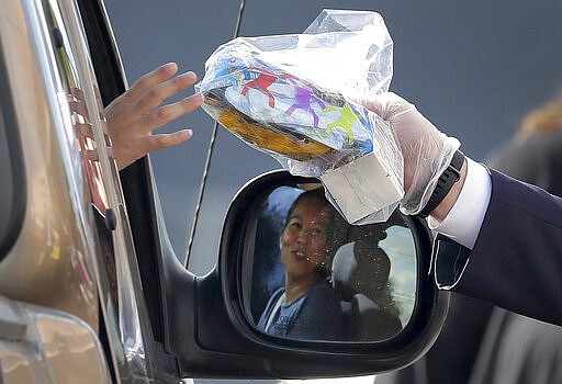 Arizona Gov. Doug Ducey, R, serves meals to school children Thursday, March 19, 2020, outside Sunset Elementary School in Phoenix. With all state schools shut down due to the COVID-19 coronavirus, many districts are continuing their distribution of breakfast and lunch curbside to kids 18 and under. (AP Photo/Matt York)