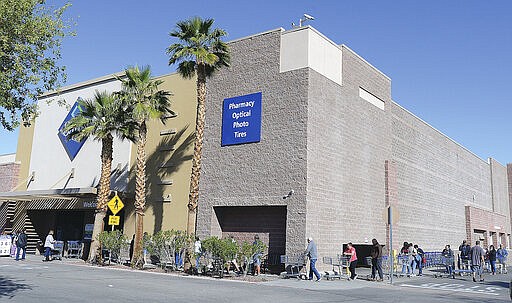 Shoppers line up around the corner of the building Thursday morning, March 19, 2020 waiting to get into Sam's Club in the Yuma Palms Regional Center in Yuma, Ariz. (Randy Hoeft/The Yuma Sun via AP)