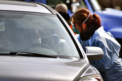 Critical care nurse Molly Spaeny, right, with St. Vincent Healthcare swabs a patient for a coronavirus test in a drive-thru testing center outside the hospital in Billings, Mont. on Friday, March 20, 2020. For most people, the new coronavirus causes only mild or moderate symptoms, such as fever and cough. For some, especially older adults and people with existing health problems, it can cause more severe illness, including pneumonia. (AP Photo/Matthew Brown)