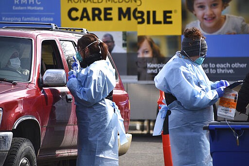 Critical care nurse Molly Spaeny, left, with St. Vincent Healthcare speaks with a patient after administering a coronavirus test in a drive-thru testing center outside the hospital in Billings, Mont. Friday, March 20, 2020. For most people, the new coronavirus causes only mild or moderate symptoms, such as fever and cough. For some, especially older adults and people with existing health problems, it can cause more severe illness, including pneumonia.(AP Photo/Matthew Brown)