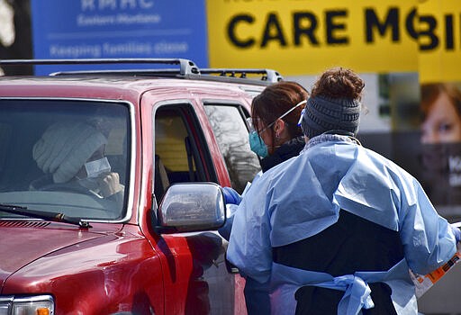 Critical care nurse Molly Spaeny, center, with emergency department technician Katrina Malson, right, of St. Vincent Healthcare speak with a patient after administering a coronavirus test in a drive-thru testing center outside the hospital in Billings, Mont. Friday, March 20, 2020. For most people, the new coronavirus causes only mild or moderate symptoms, such as fever and cough. For some, especially older adults and people with existing health problems, it can cause more severe illness, including pneumonia.(AP Photo/Matthew Brown)