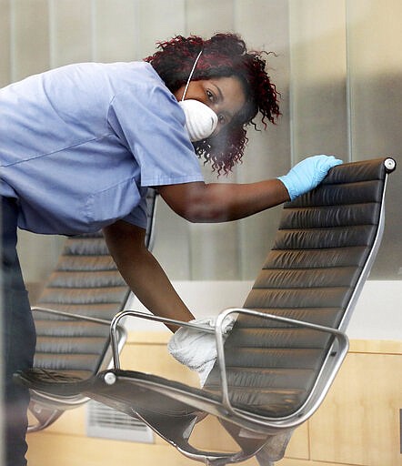 A worker sanitizes furniture at the downtown Minneapolis Public Library, a day after the library temporarily closed and was seen Wednesday, March 18, 2020, in Minneapolis, Minn. (David Joles/Star Tribune via AP)