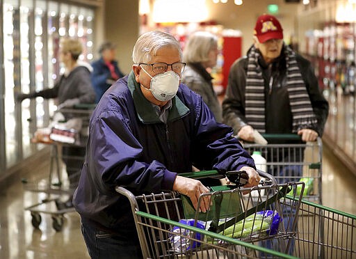 Shopper Merlin Smith, 82, of Edina navigates the aisles of Lunds and Byerlys during an early morning hour devoted to older shoppers and shoppers with health conditions Thursday, March 19, 2020, in Edina, Minn. Smith was also shopping for his wife who has heart issues and was home. Some supermarket retailers across the world and Twin Cities are creating an early bird shopping time from 7-8 a.m. for older shoppers to protect them from COVID-19 and coronavirus.  (Merlin Smith/Star Tribune via AP)