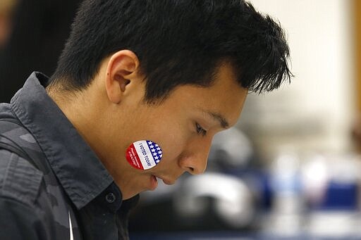 In this March 5, 2020, photo Angel Tapia displays his &quot;I Voted Today&quot; sticker as students participate in their own Democratic presidential preference election and voter registration drive at Maryvale High School in Phoenix. At the school hundreds of students who will turn 18 before Election Day were registered to vote. (AP Photo/Ross D. Franklin)