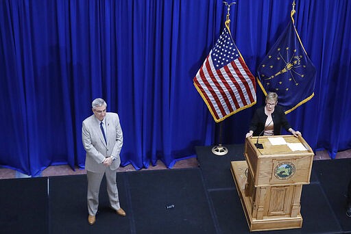 Indiana Gov. Eric Holcomb listens as Secretary of State Connie Lawson speaks during a news conference at the Statehouse, Friday, March 20, 2020, in Indianapolis. Holcomb said during the news conference with the state GOP and Democratic chairmen that the Indiana primary will be held on June 2 because of concern about the coronavirus pandemic. (AP Photo/Darron Cummings)