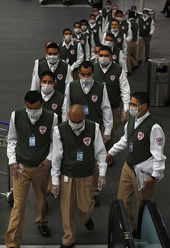 Airport security workers wear face masks as a precaution against the spread of the new coronavirus at Benito Juarez International Airport in Mexico City, Friday, March 20, 2020. (AP Photo/Marco Ugarte)