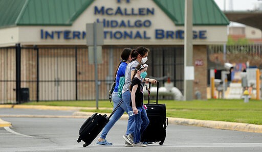 Pedestrians wearing protective masks cross from Mexico to Texas at the McAllen Hidalgo International Bridge, Friday, March 20, 2020, in Hidalgo, Texas. President Donald Trump announced Friday the U.S.-Mexico border will be closed to nonessential travel to further help stem the spread of the coronavirus. (AP Photo/Eric Gay)