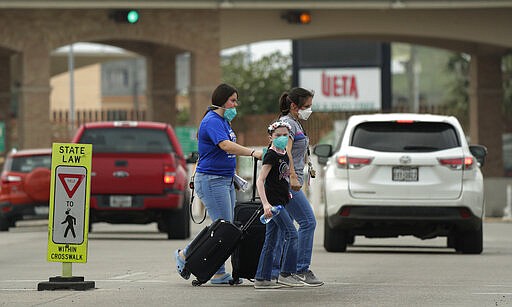 Pedestrians wearing protective masks cross from Mexico to Texas at the McAllen Hidalgo International Bridge, Friday, March 20, 2020, in Hidalgo, Texas. President Donald Trump announced Friday the U.S.-Mexico border will be closed to nonessential travel to further help stem the spread of the coronavirus. (AP Photo/Eric Gay)