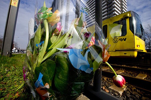 -FILE- In this Tuesday March 19, 2019, file image, a tram passes flowers placed at the site of a shooting incident on a tram, in Utrecht, Netherlands. The trial of a Dutch man of Turkish descent is starting Monday March 2, 2020, for allegedly opening fire on a tram in the central city of Utrecht last year, killing four people in what prosecutors say was a terror attack. (AP Photo/Peter Dejong, File)