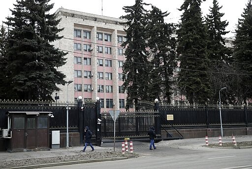 People walk past the building of the Chinese Embassy in Moscow, Russia, Friday, March 20, 2020. According to court filings and Russian defense lawyer Sergei Malik, authorities in Moscow are detaining and deporting some Chinese nationals for violating quarantine procedures the city government mandated in response to the coronavirus. For most people the coronavirus causes mild or moderate symptoms, but for some it can cause severe illness.(AP Photo/Pavel Golovkin)