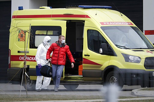 A medical worker helps a man, suspected of having the coronavirus infection, to get out from an ambulance at a hospital outside Moscow, Russia, Friday, March 20, 2020. The Russian government says that it has decided to bar entry to all foreigners starting Wednesday. For most people, the new coronavirus causes only mild or moderate symptoms, such as fever and cough. For some, especially older adults and people with existing health problems, it can cause more severe illness, including pneumonia. (AP Photo/Pavel Golovkin)