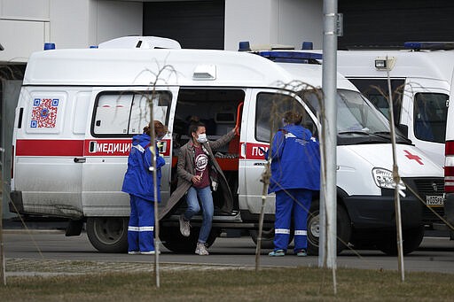 Medical workers escort a man, suspected of having the coronavirus infection, to get out from an ambulance at a hospital outside Moscow, Russia, Friday, March 20, 2020.  The Russian government says that it has decided to bar entry to all foreigners starting Wednesday. For most people, the new coronavirus causes only mild or moderate symptoms, such as fever and cough. For some, especially older adults and people with existing health problems, it can cause more severe illness, including pneumonia. (AP Photo/Pavel Golovkin)